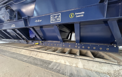 Close-up of a blue hopper wagon with an open unloading system above a bulk goods pit