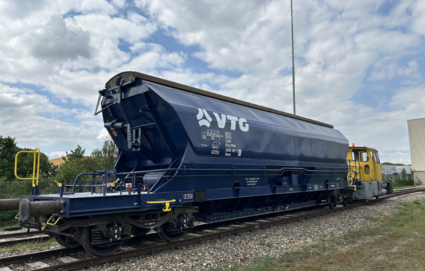 VTG hopper wagon on a shunting track with locomotive in the background.