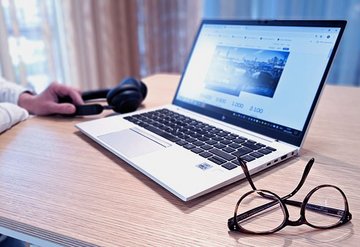 Smiling woman in front of her laptop with window panes in background.